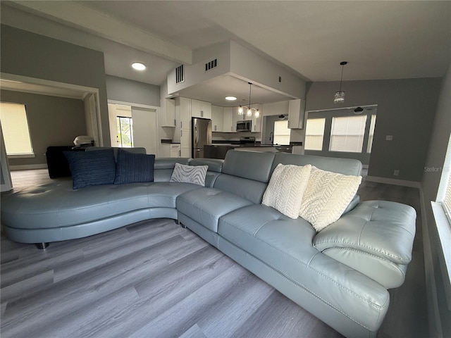 living room with an inviting chandelier, lofted ceiling, and light wood-type flooring