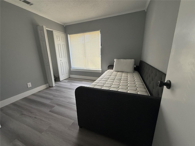 bedroom featuring a textured ceiling, light hardwood / wood-style flooring, a closet, and ornamental molding