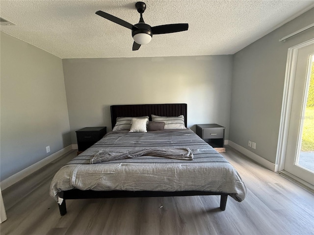 bedroom with multiple windows, ceiling fan, light hardwood / wood-style flooring, and a textured ceiling