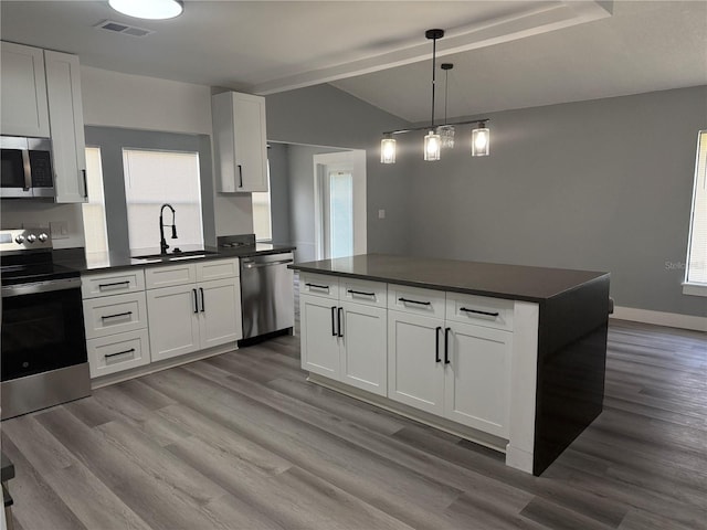 kitchen with stainless steel appliances, sink, white cabinets, light hardwood / wood-style floors, and hanging light fixtures