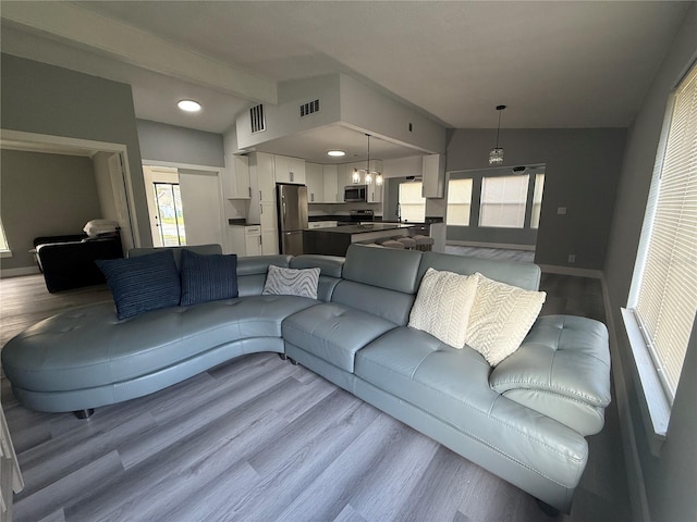 living room with vaulted ceiling with beams and light hardwood / wood-style flooring