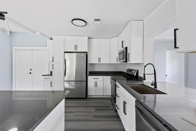 kitchen featuring white cabinetry, sink, stainless steel appliances, dark hardwood / wood-style floors, and dark stone countertops