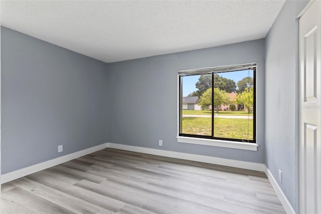 unfurnished room featuring a textured ceiling, light hardwood / wood-style flooring, and a healthy amount of sunlight