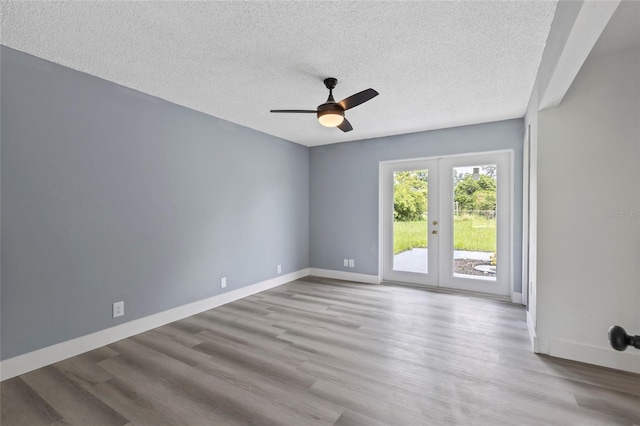 empty room featuring ceiling fan, french doors, a textured ceiling, and light wood-type flooring