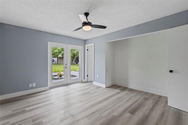 empty room with french doors, a textured ceiling, light hardwood / wood-style flooring, and ceiling fan