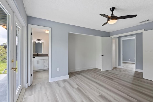 unfurnished bedroom featuring access to outside, ceiling fan, a textured ceiling, connected bathroom, and light hardwood / wood-style floors