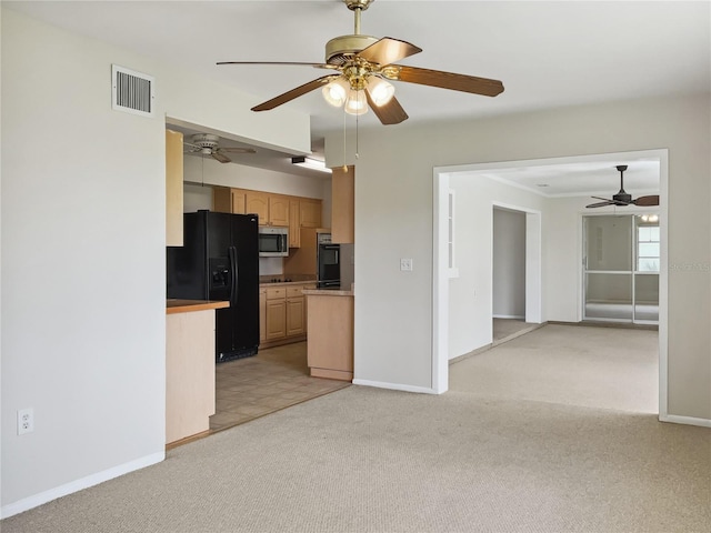 kitchen featuring light carpet, black appliances, and light brown cabinetry