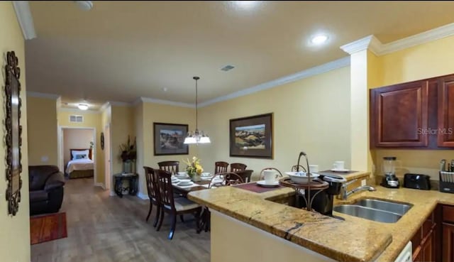 kitchen with sink, light stone counters, crown molding, kitchen peninsula, and hardwood / wood-style flooring