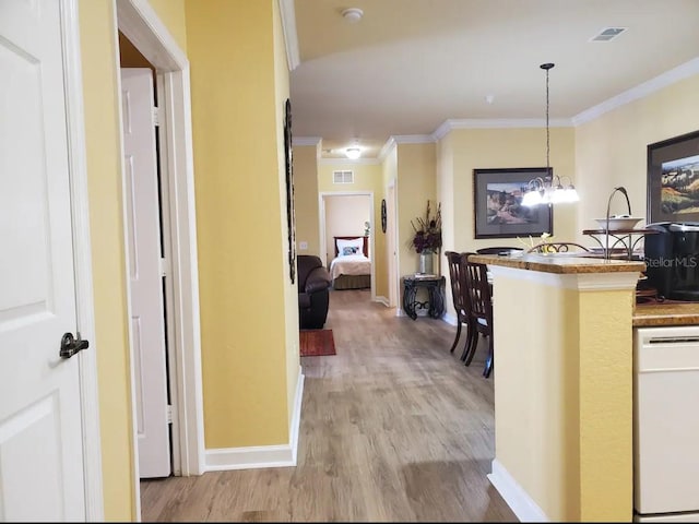 corridor featuring light hardwood / wood-style floors, ornamental molding, and an inviting chandelier