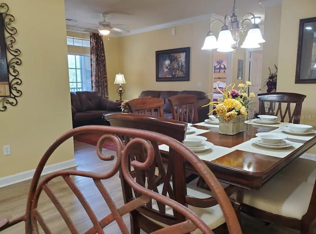 dining space with hardwood / wood-style floors, ceiling fan with notable chandelier, and ornamental molding