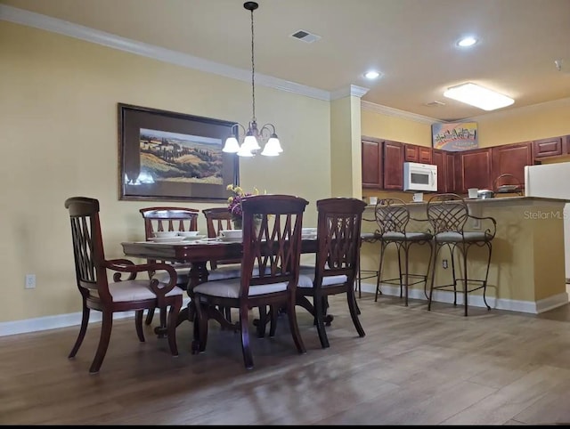 dining space with a notable chandelier, crown molding, and wood-type flooring