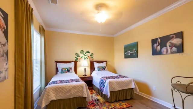 bedroom with hardwood / wood-style floors, multiple windows, and crown molding