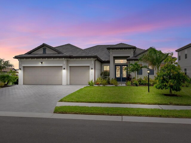 view of front of property with a garage and a lawn