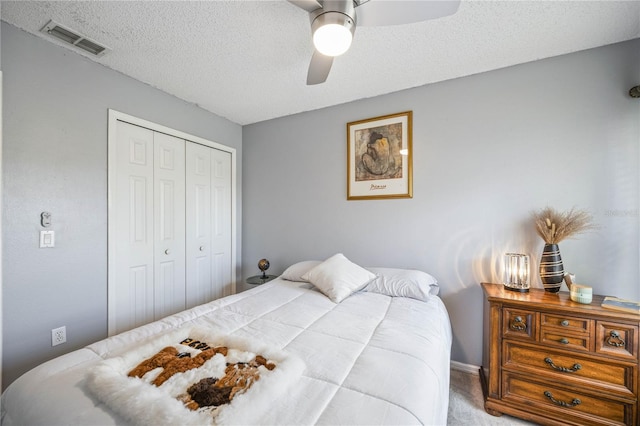 carpeted bedroom with a ceiling fan, a closet, visible vents, and a textured ceiling