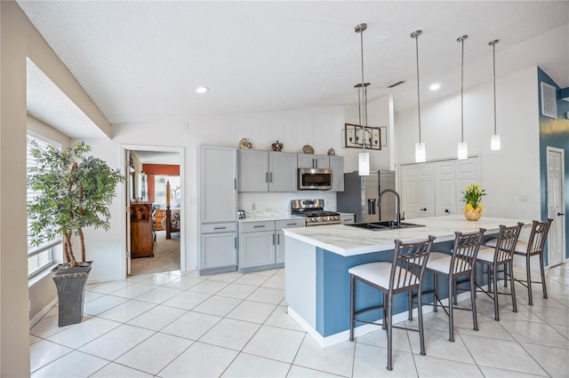 kitchen with a spacious island, stainless steel appliances, gray cabinetry, pendant lighting, and a sink