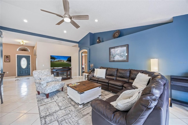 living room with light tile patterned floors, arched walkways, vaulted ceiling, and a ceiling fan