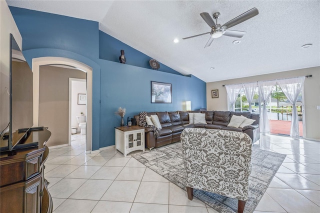 living area featuring lofted ceiling, light tile patterned floors, arched walkways, and a ceiling fan