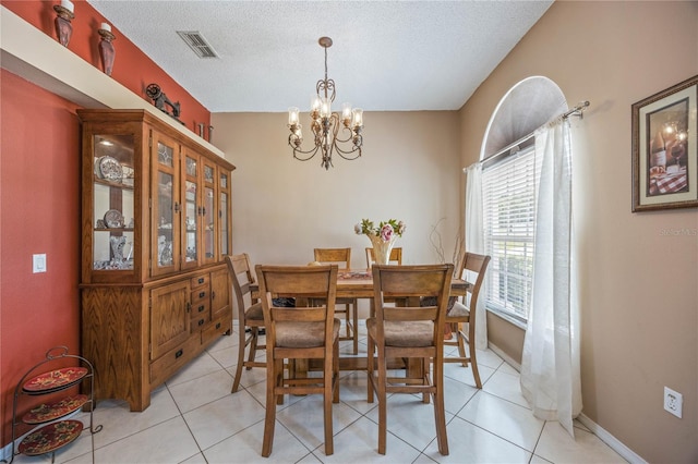 dining area featuring a textured ceiling, light tile patterned flooring, visible vents, and an inviting chandelier