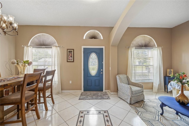 entryway with plenty of natural light, a textured ceiling, baseboards, and light tile patterned floors