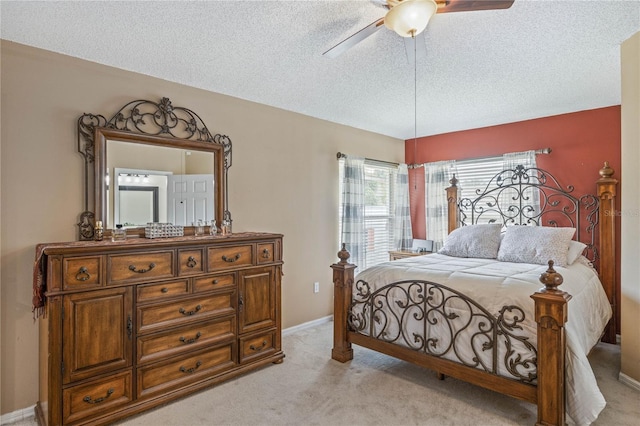 bedroom with a ceiling fan, light carpet, a textured ceiling, and baseboards