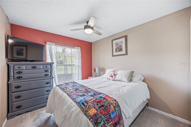 bedroom featuring a textured ceiling, ceiling fan, baseboards, and light colored carpet