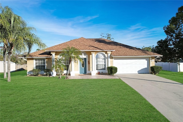 view of front of house with driveway, a front lawn, fence, and stucco siding