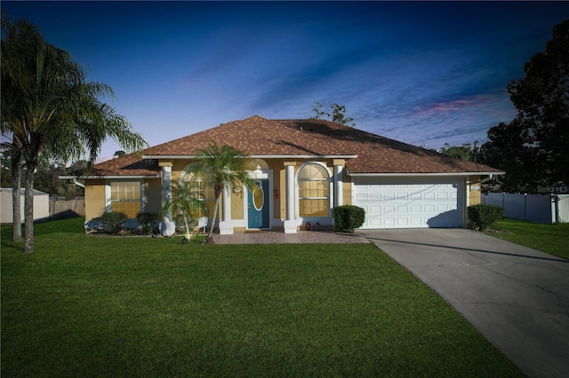 view of front of property featuring concrete driveway, fence, a front lawn, and stucco siding