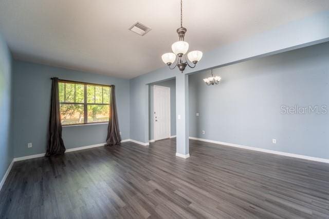 empty room featuring a chandelier and dark wood-type flooring