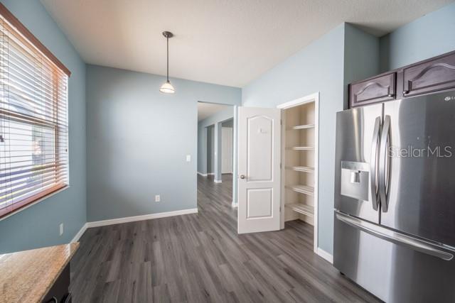 kitchen with decorative light fixtures, dark hardwood / wood-style floors, dark brown cabinetry, and stainless steel refrigerator with ice dispenser