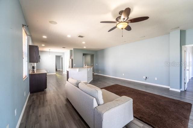 living room with ceiling fan and dark wood-type flooring