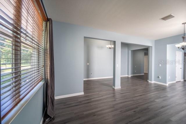 unfurnished room featuring a chandelier and dark hardwood / wood-style flooring