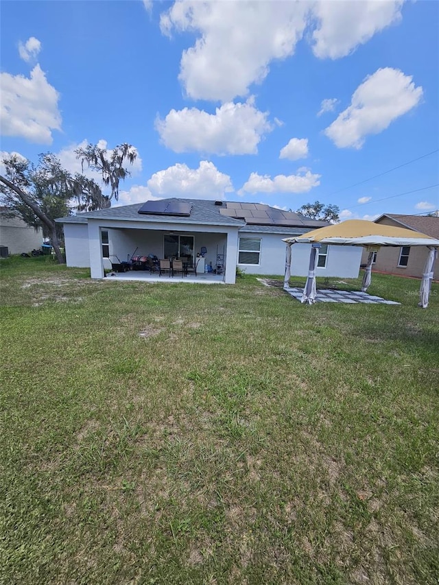 back of house with a lawn and solar panels