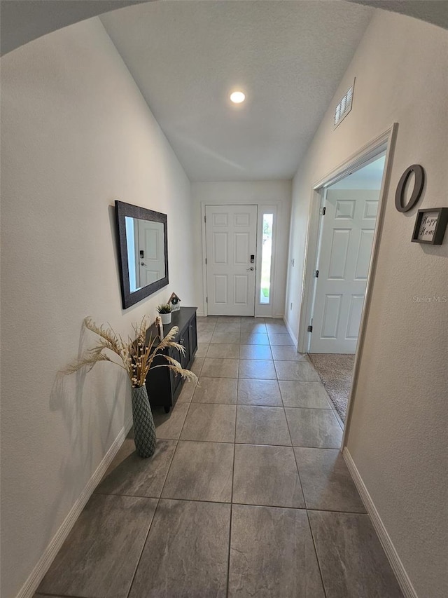 foyer entrance featuring tile patterned flooring and lofted ceiling