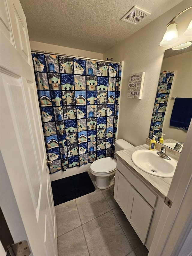 bathroom with tile patterned flooring, toilet, a textured ceiling, and vanity