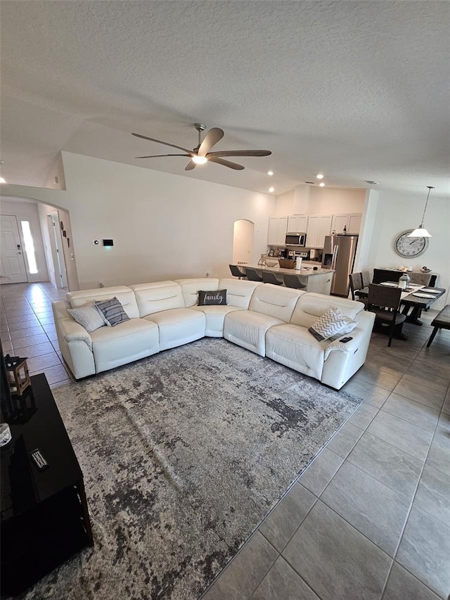 living room with ceiling fan, a textured ceiling, and light tile patterned flooring