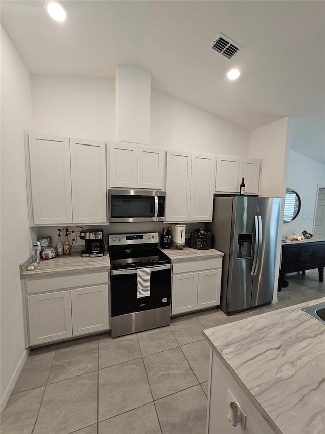 kitchen with light tile patterned floors, appliances with stainless steel finishes, high vaulted ceiling, and white cabinets