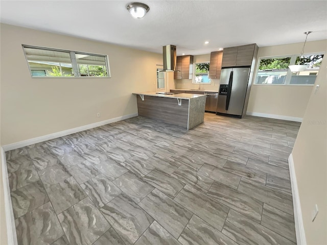 kitchen with a wealth of natural light, a breakfast bar area, kitchen peninsula, and appliances with stainless steel finishes