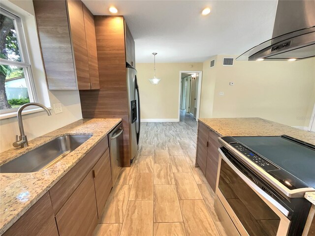 kitchen featuring extractor fan, appliances with stainless steel finishes, decorative light fixtures, sink, and light stone counters