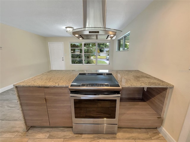 kitchen with stainless steel range with electric cooktop, light stone counters, island range hood, and light tile patterned floors