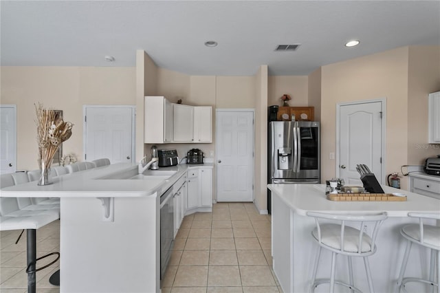 kitchen with white cabinetry, a kitchen bar, light tile patterned floors, and stainless steel appliances