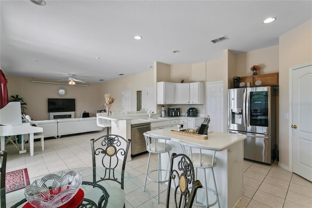 kitchen featuring ceiling fan, white cabinetry, a center island, and stainless steel appliances