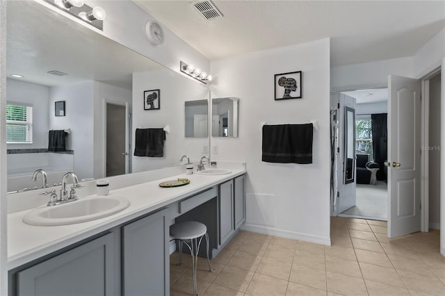 bathroom with a washtub, plenty of natural light, dual bowl vanity, and tile patterned floors