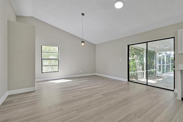 spare room featuring light hardwood / wood-style floors, a textured ceiling, and high vaulted ceiling