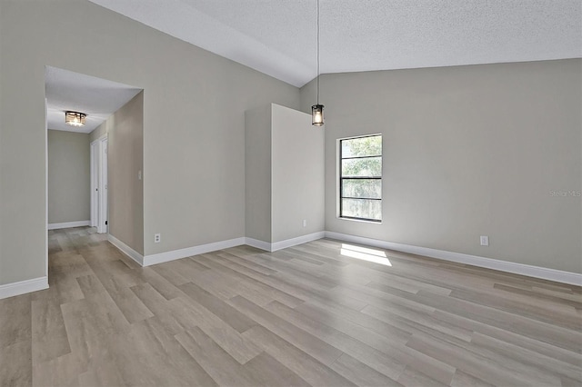 spare room featuring high vaulted ceiling, a textured ceiling, and light wood-type flooring