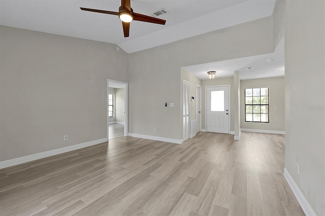 unfurnished living room with light hardwood / wood-style flooring, a textured ceiling, lofted ceiling, and ceiling fan