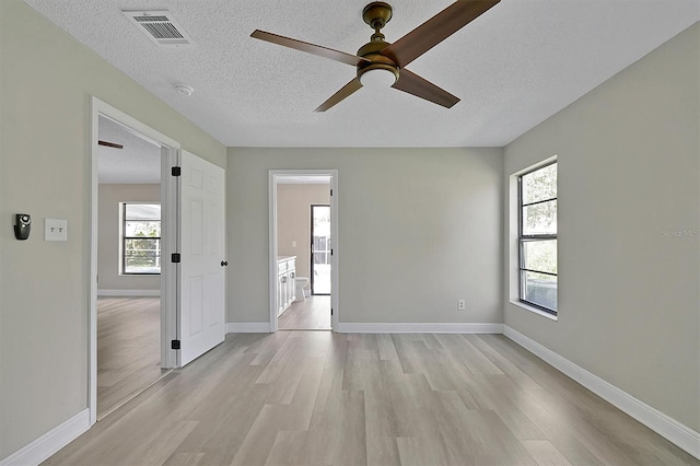 unfurnished room with light hardwood / wood-style flooring, a textured ceiling, a healthy amount of sunlight, and ceiling fan