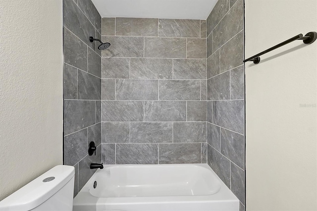 bathroom featuring tiled shower / bath and toilet