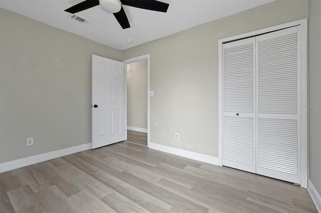 unfurnished bedroom with light wood-type flooring, a closet, visible vents, and baseboards