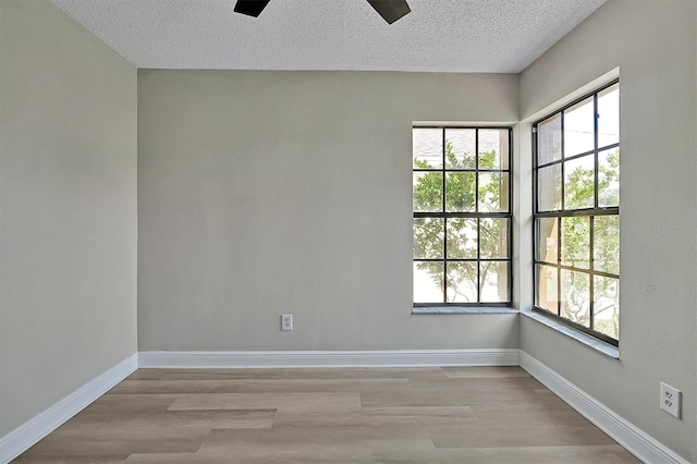 unfurnished room with a textured ceiling, light hardwood / wood-style floors, and ceiling fan