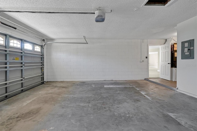 garage featuring a garage door opener, concrete block wall, and electric panel